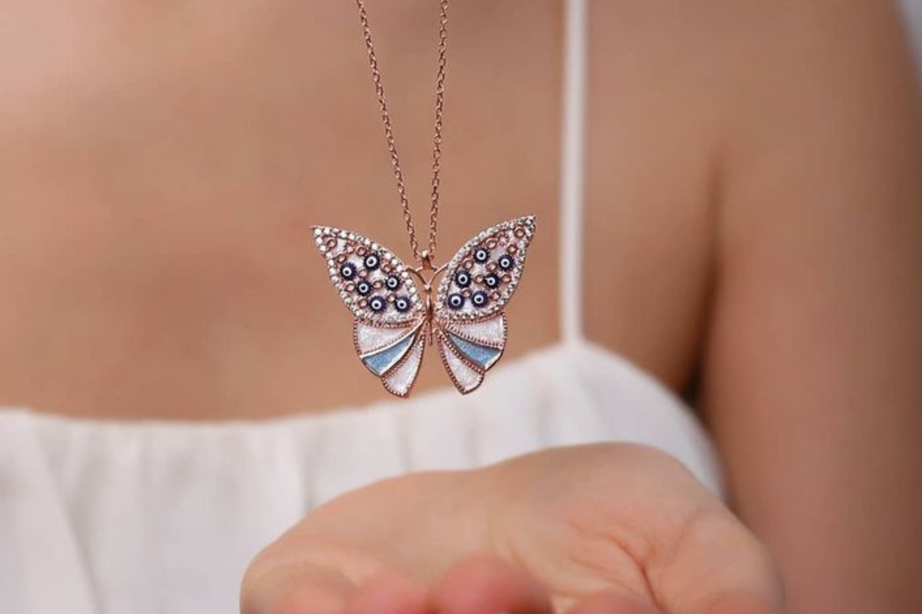 A lady holding a butterfly necklace