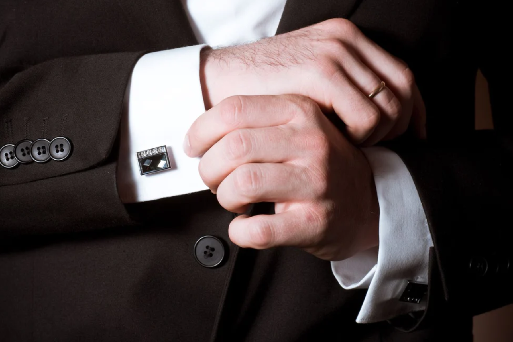 A man wearing a formal suit with formal cufflinks