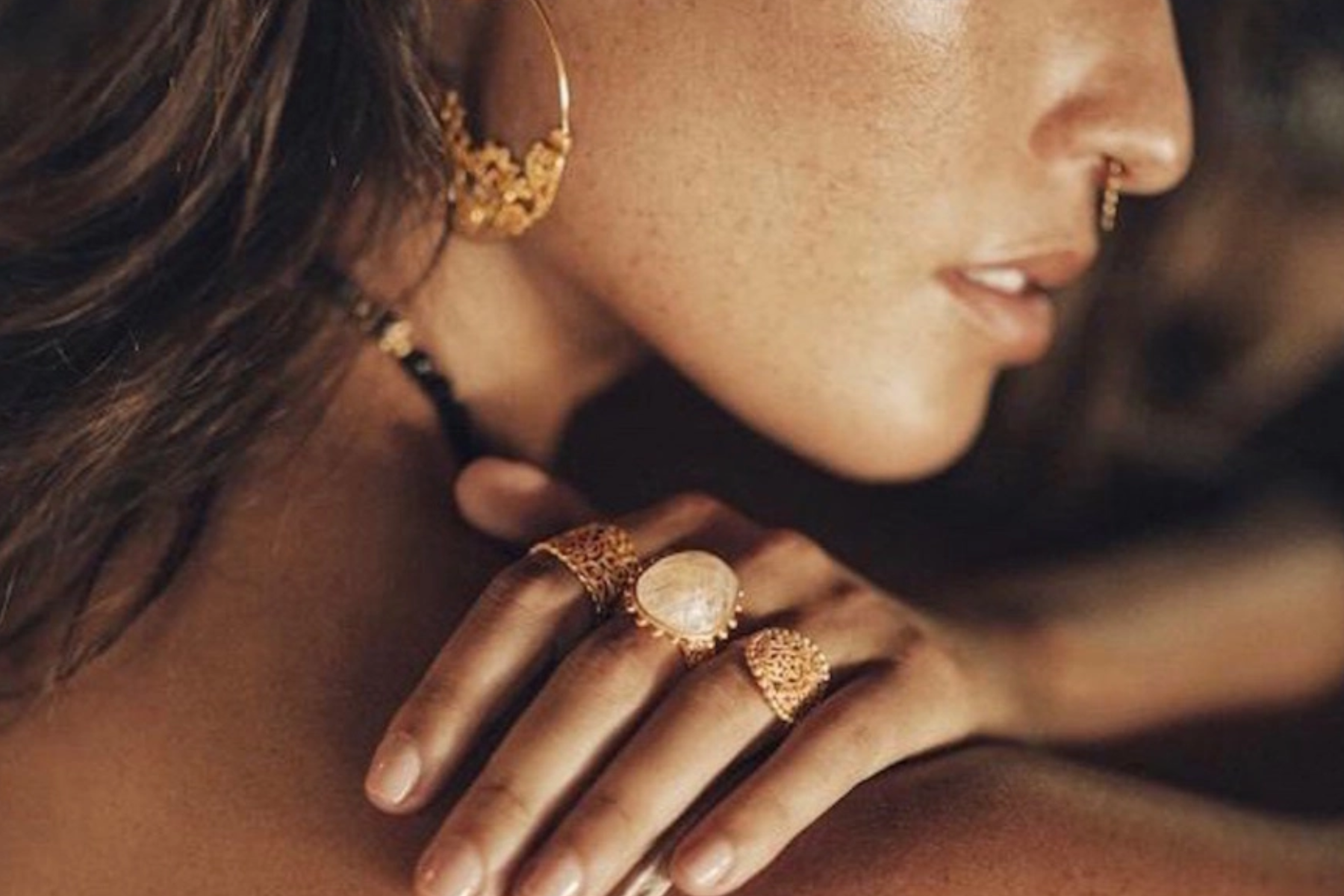 A modern woman poses with gold jewelry