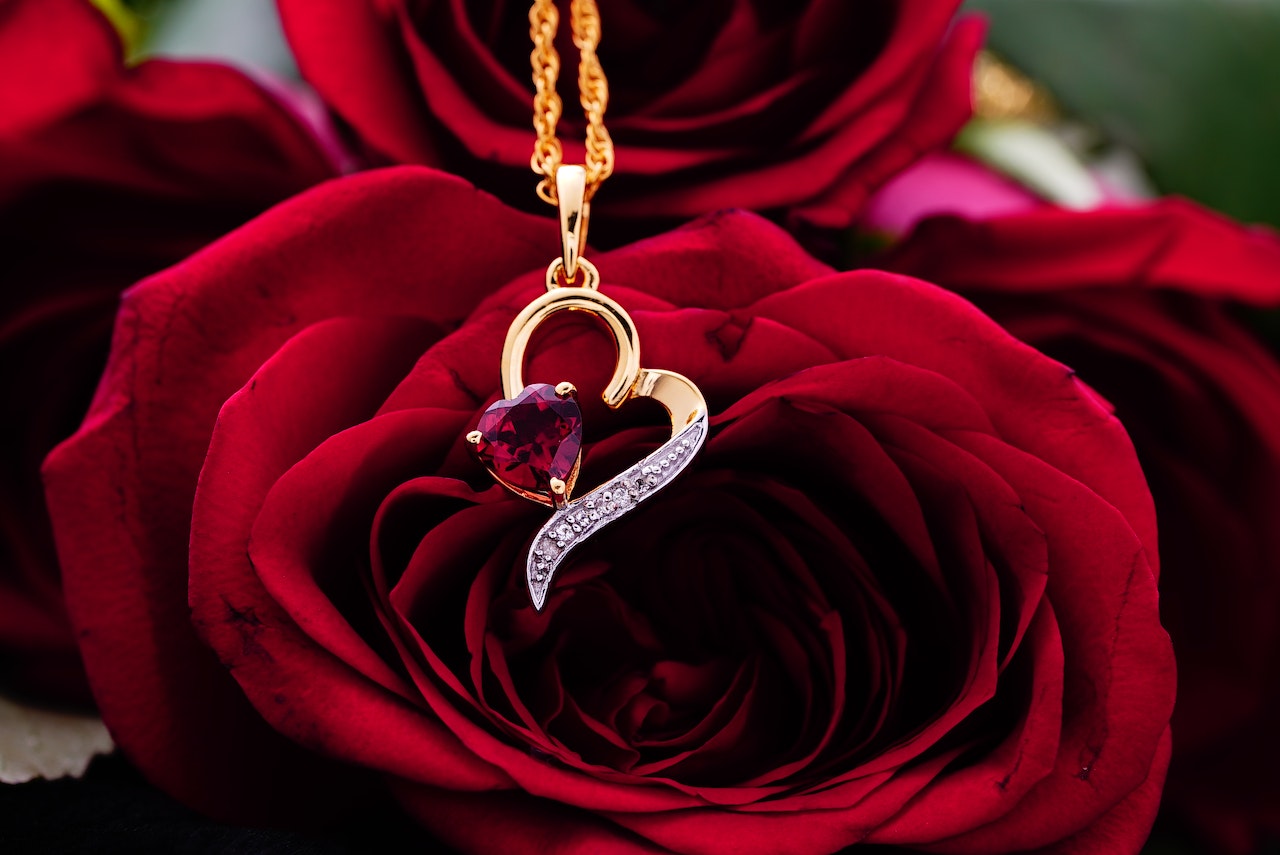 Heart shaped necklace on red roses