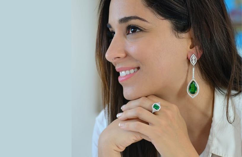 A woman smiles while wearing her emerald ring and earring