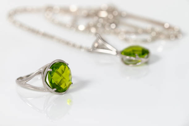 A cushion cut chrysolite ring is paired with a chrysolite necklace on a blurred background