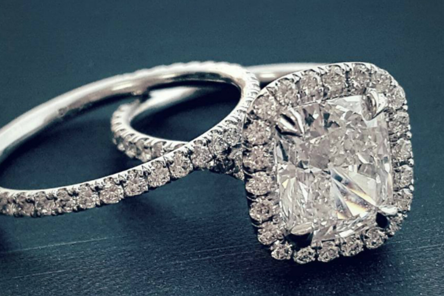 A cushion-cut diamond engagement ring resting on a plain diamond ring