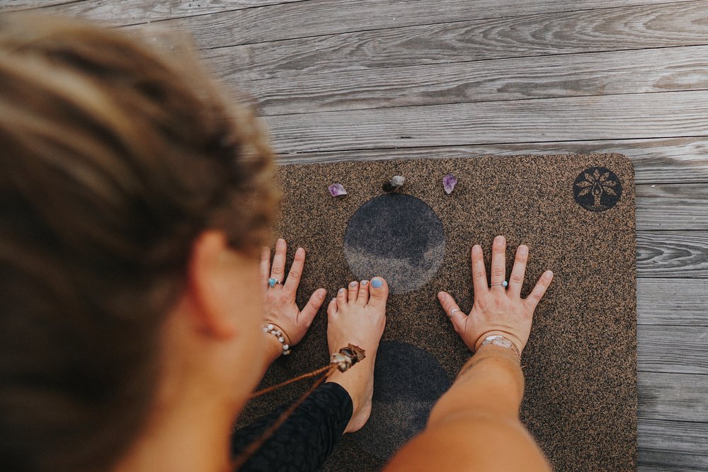 Woman doing yoga while staring at 3 small quartz crystal on the floor
