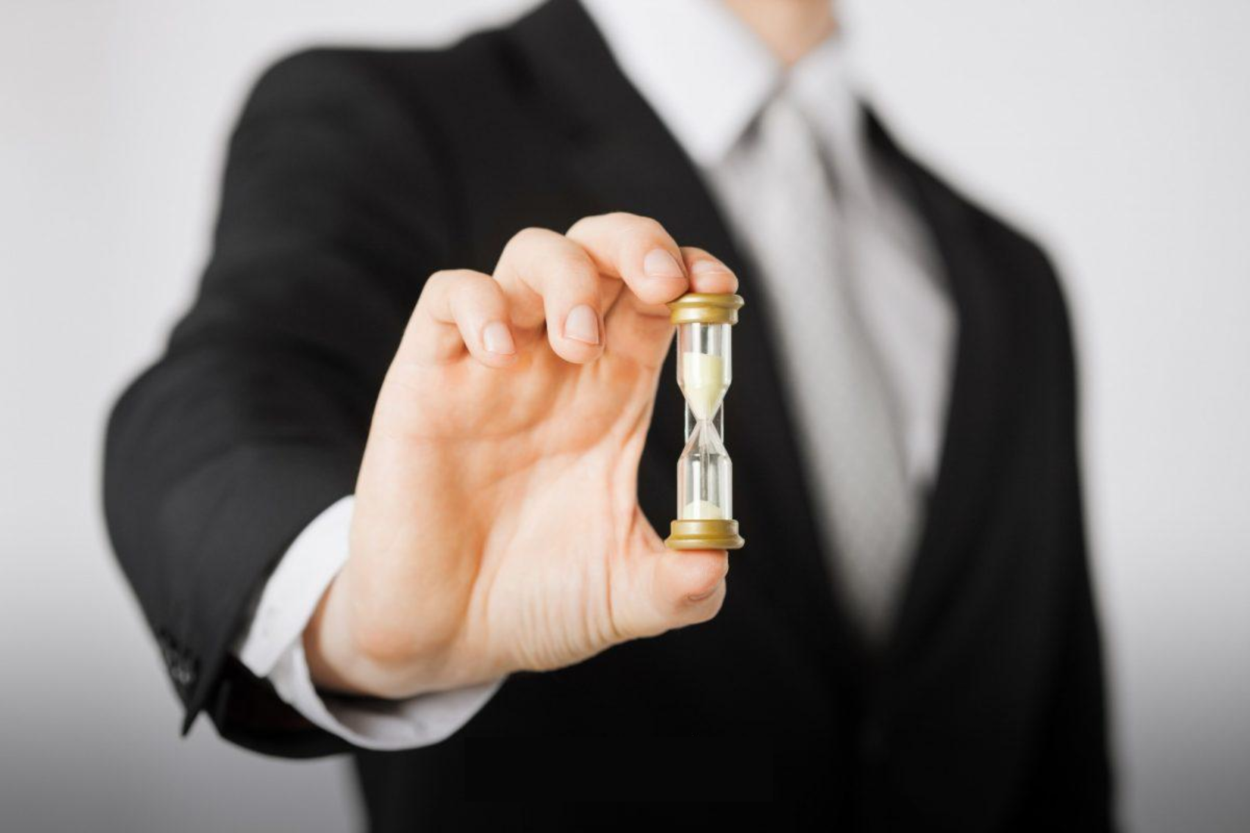 A man in a business suit holding a sand timer