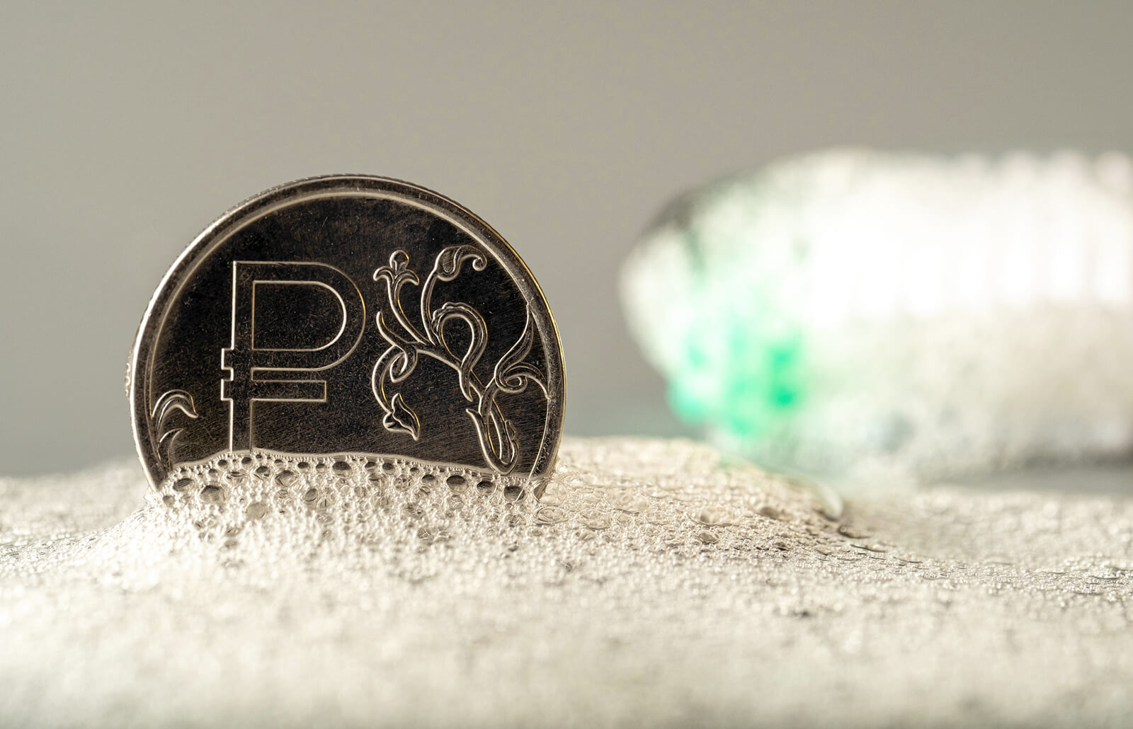A coin on a bubble alongside a soft brush