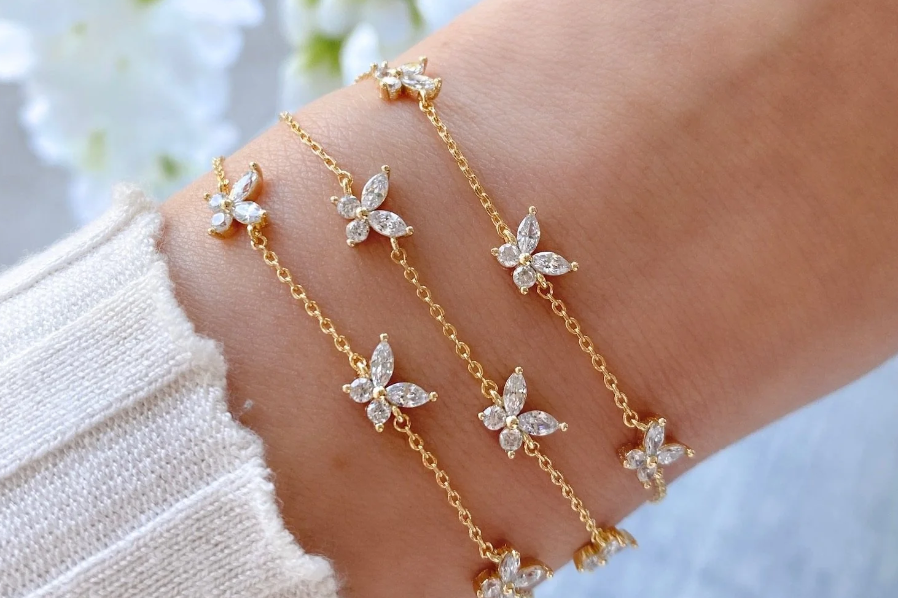 The wrist of a woman is adorned with three-layered butterfly bracelets