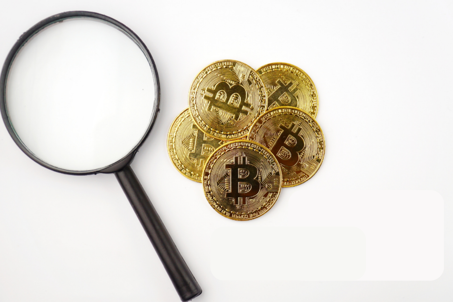 Bitcoins next to a magnifying glass