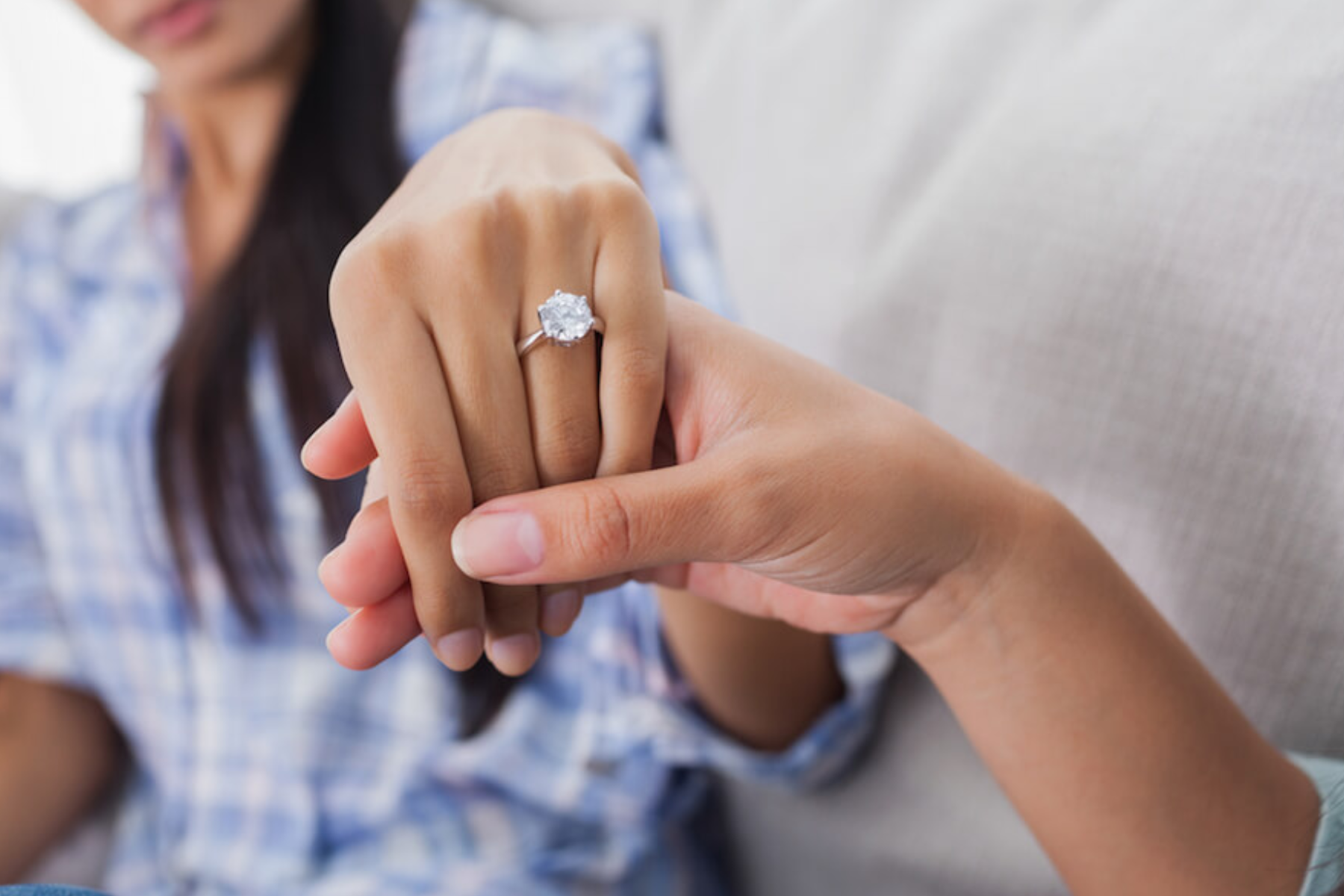 A man holding his fiancee's hand to show the solitaire engagement ring