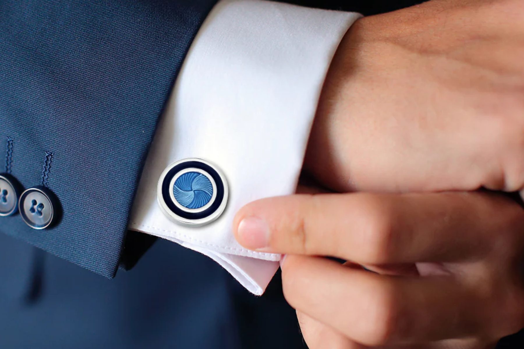 A man attaches a cufflink made of blue enamel
