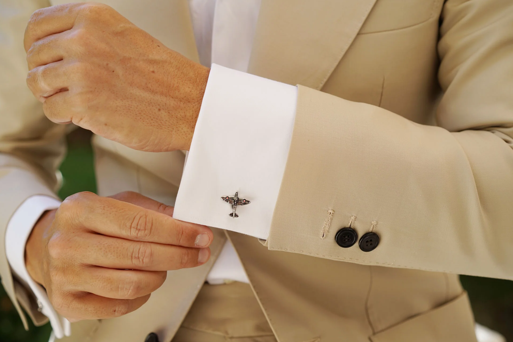 A man sporting a formal suit and airplane cufflinks