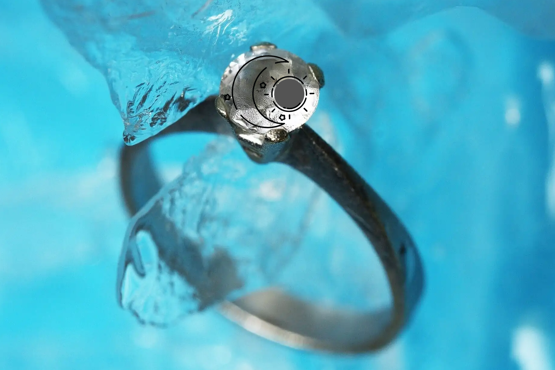 A platinum ring with sun and moon symbols that has been immersed in water