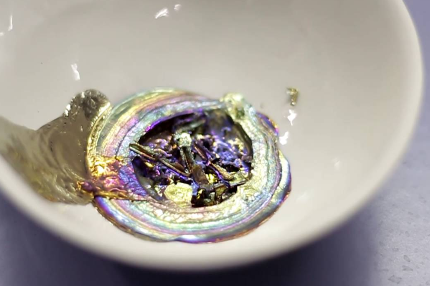 A white bowl with melted bismuth material inside