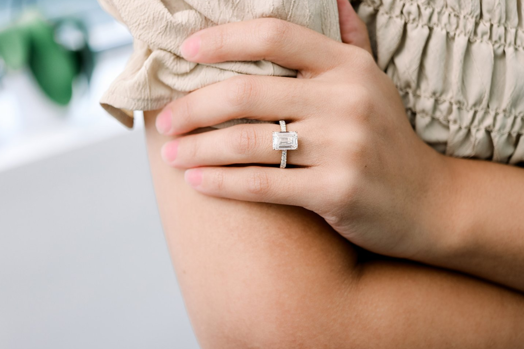 Emerald-cut diamond engagement ring on the hand of a woman posing for a half-body shot