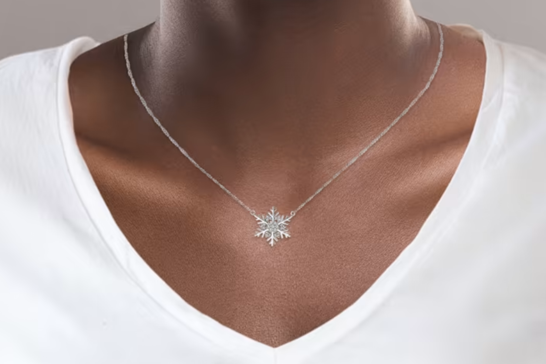 A man with dark skin wearing a necklace with a snowflake pendant