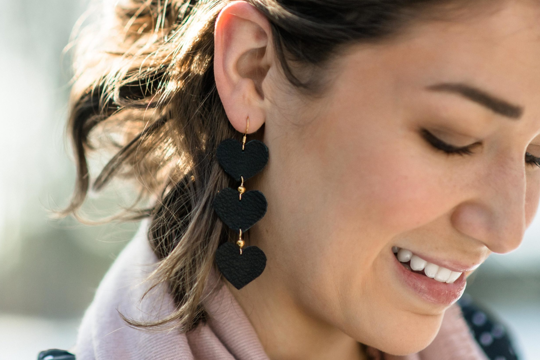 A woman in public wearing three-layered heart leather earrings