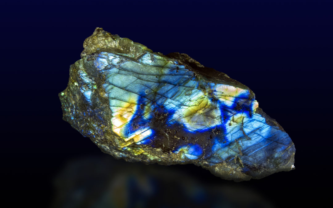 An image of a raw labradorite stone placed on a dark background