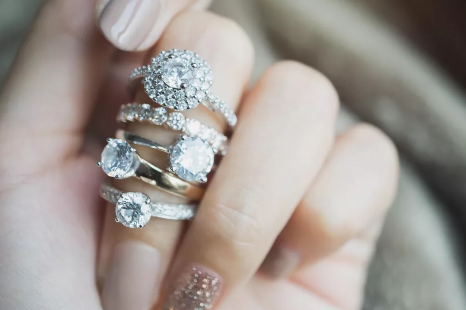 Five diamond engagement rings on a woman's finger