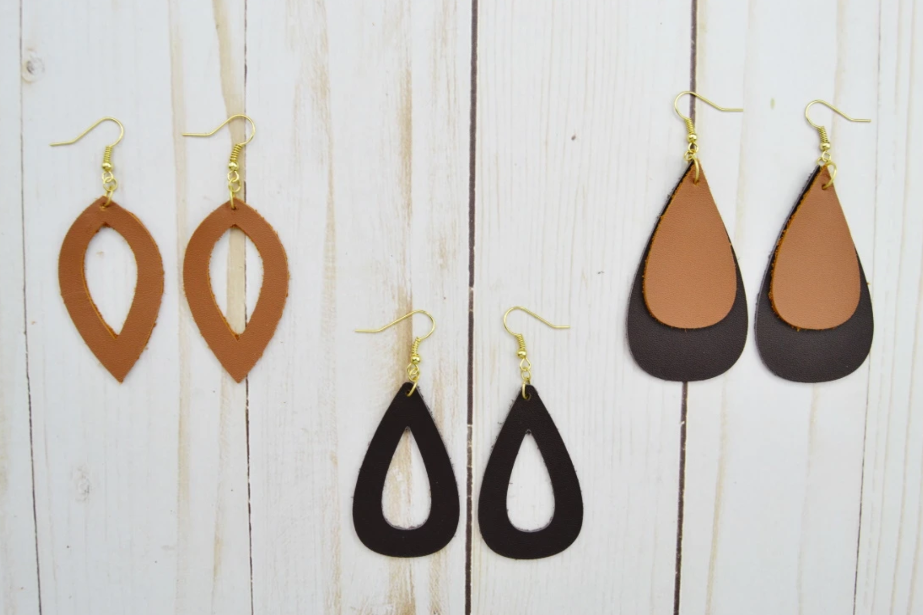 Three distinct styles of leather earrings on a wooden base