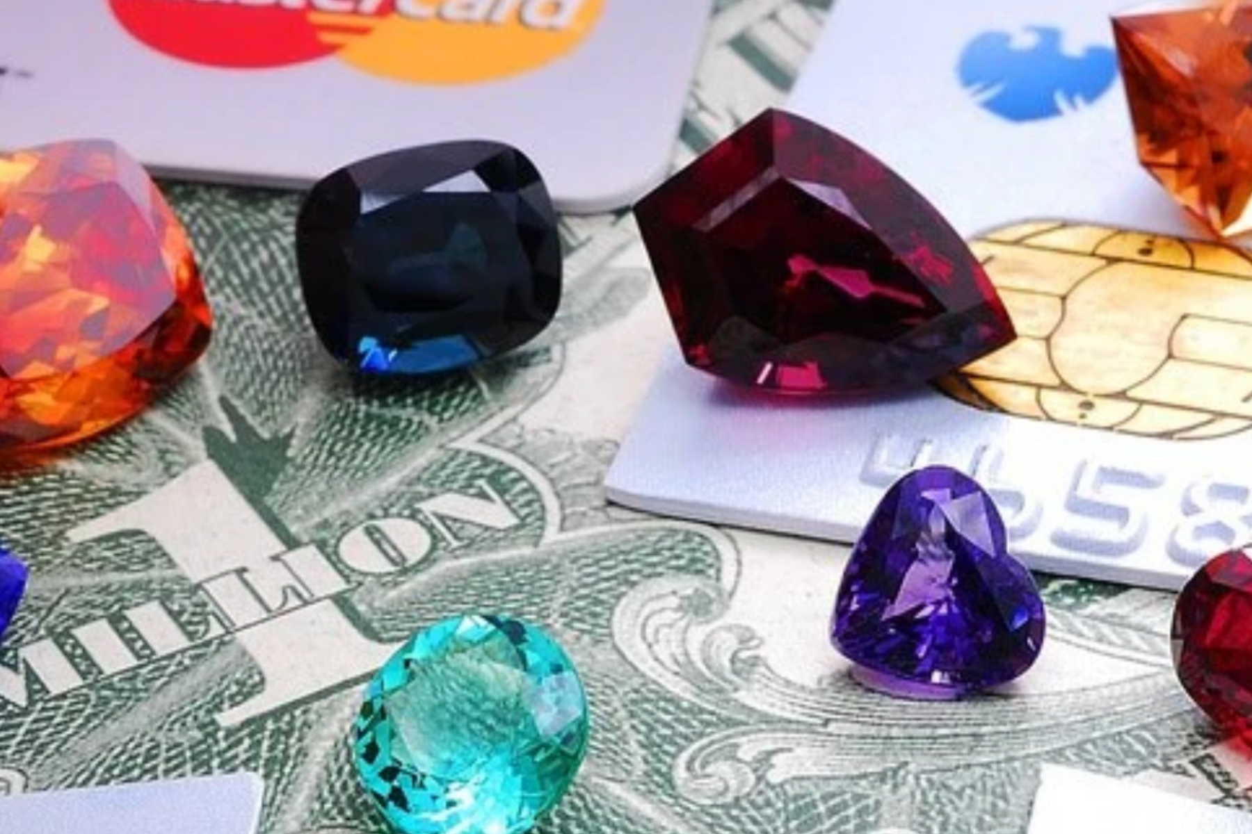 Various gemstones on top of dollar bills and credit cards
