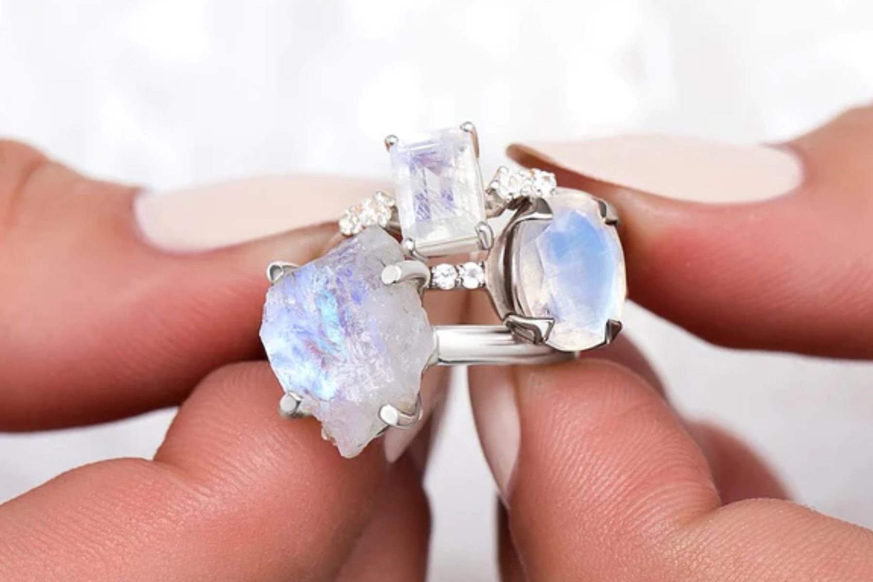 Moonstone rings of varying sizes held by a woman's finger