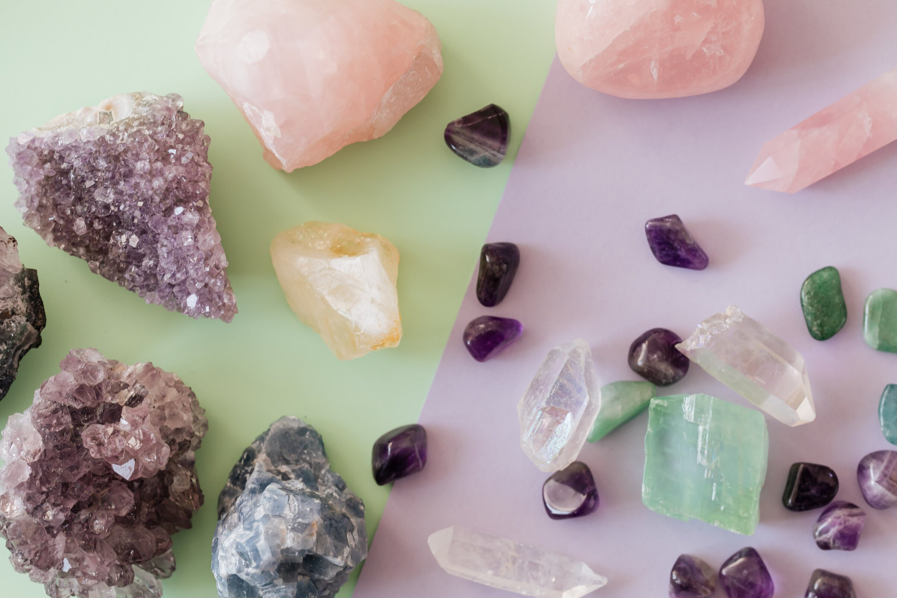 Gemstones of various types are arranged on a background of green and violet hues