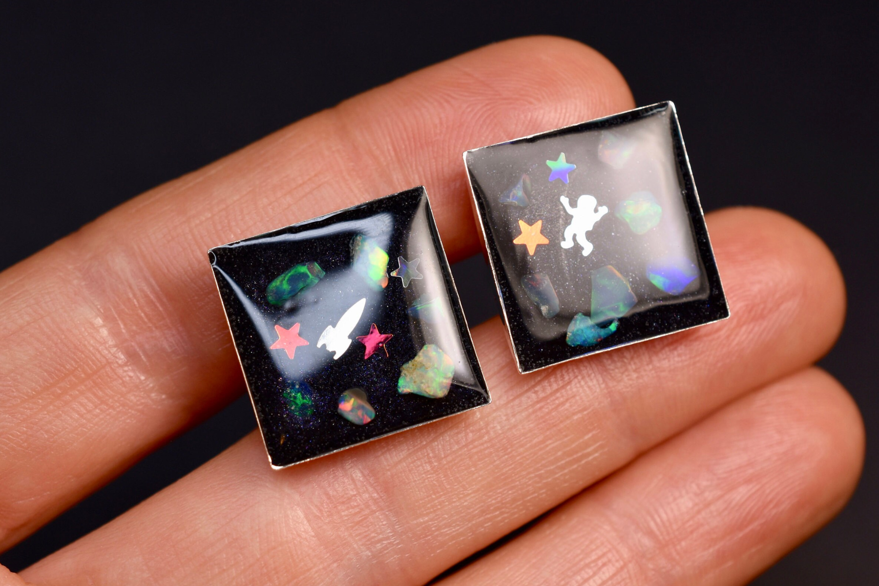 A man's hand carrying cufflinks with a space theme