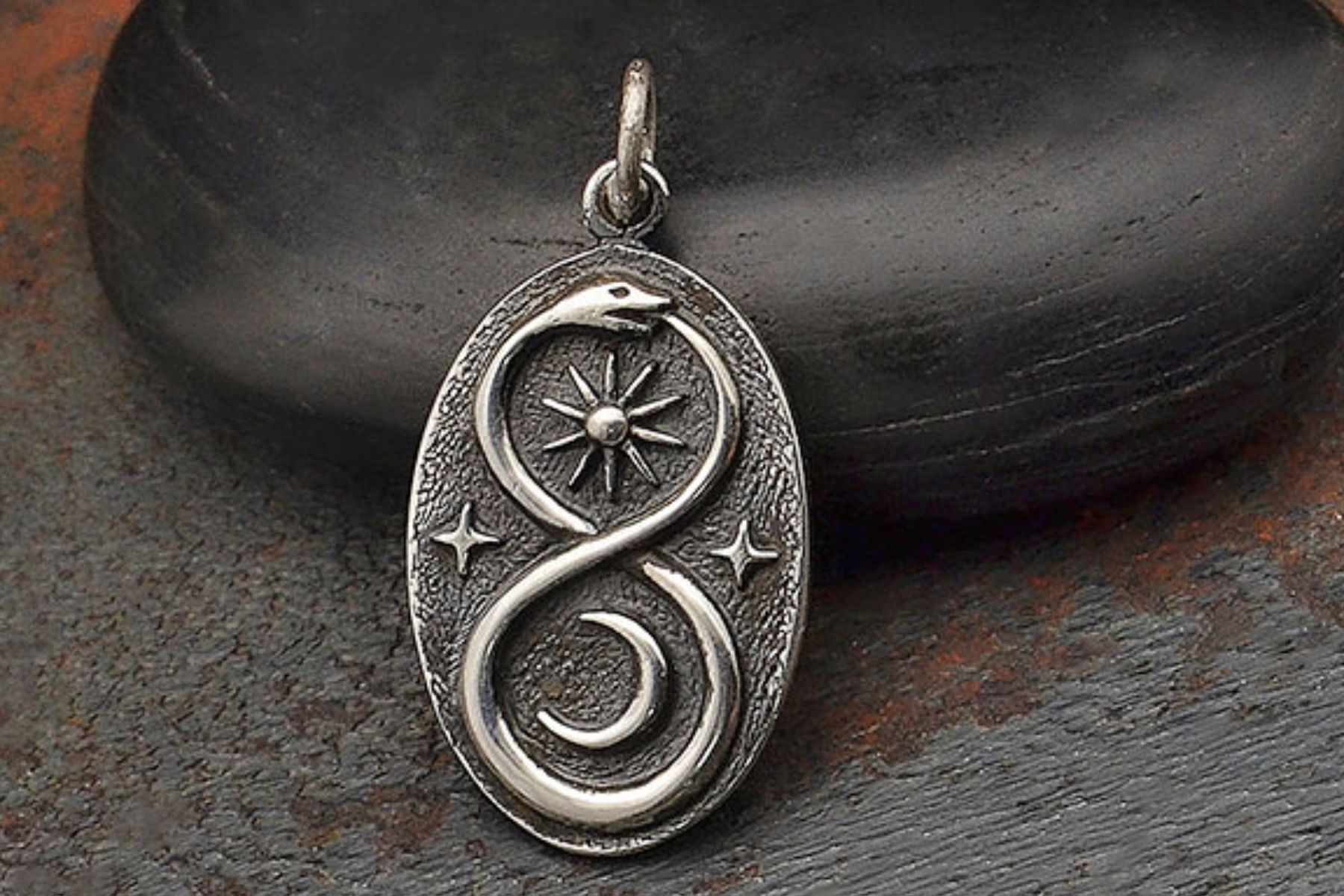 A platinum pendant with sun, moon, and snake signs