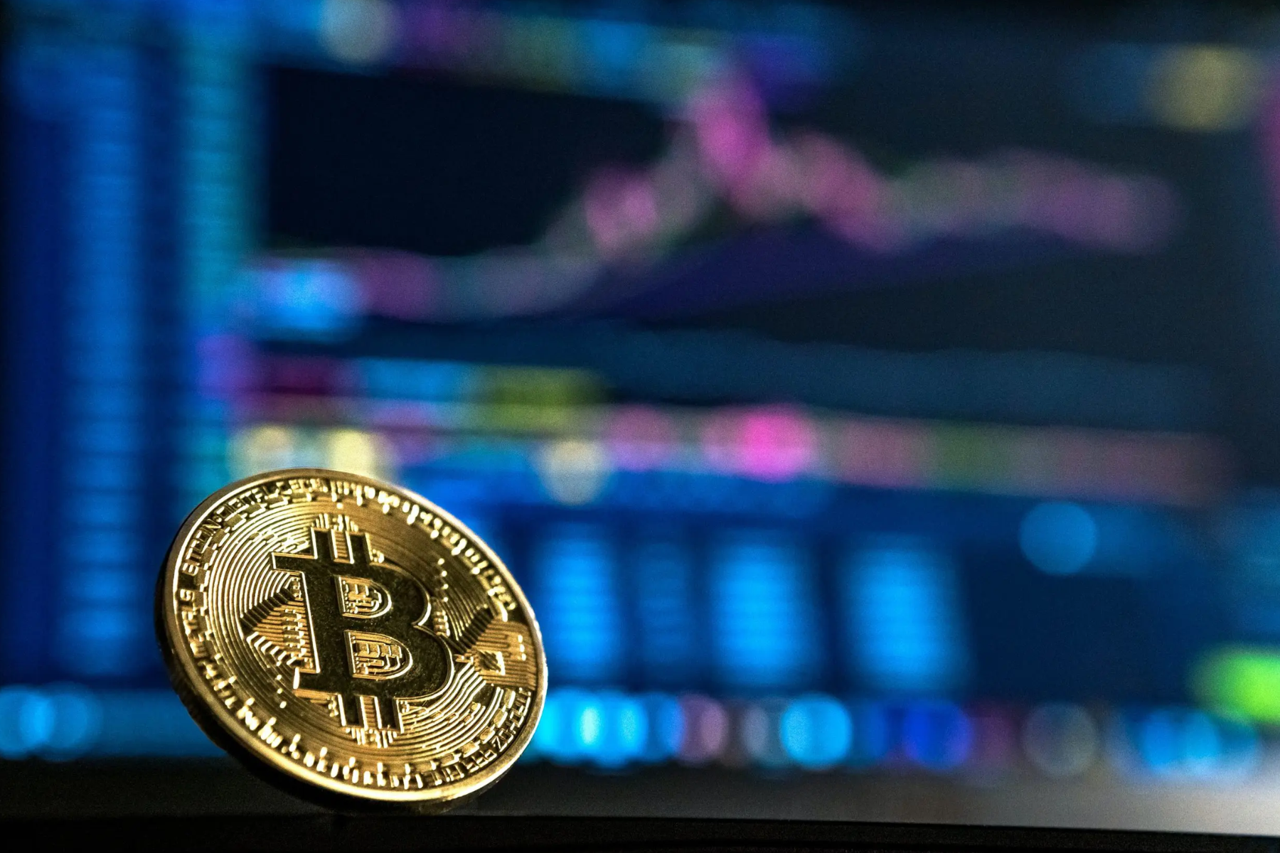 A bitcoin in front of a hazy monitor display