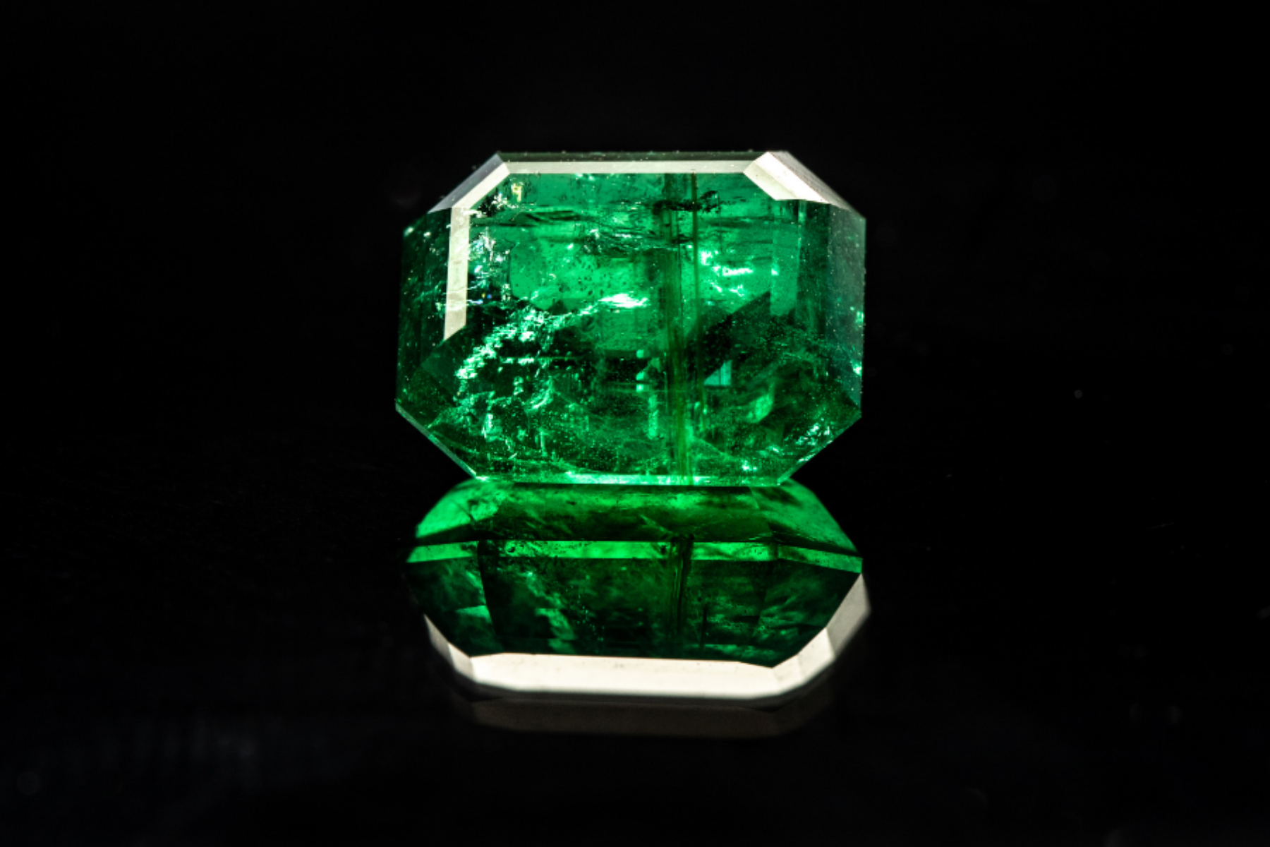 The image depicts an octagonal-cut emerald set against a dark background