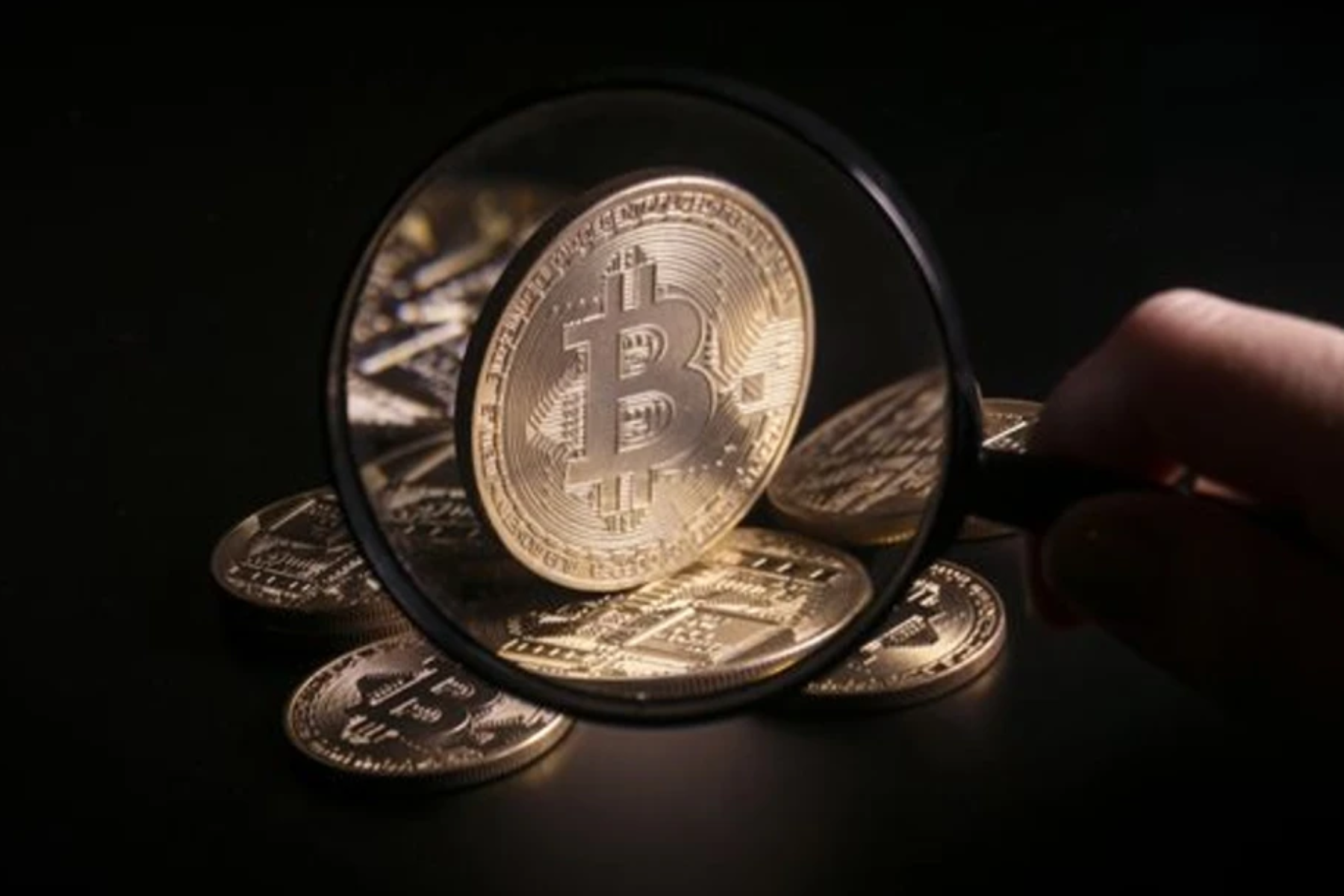 A close-up view of a Bitcoin with a magnifying glass in front of it