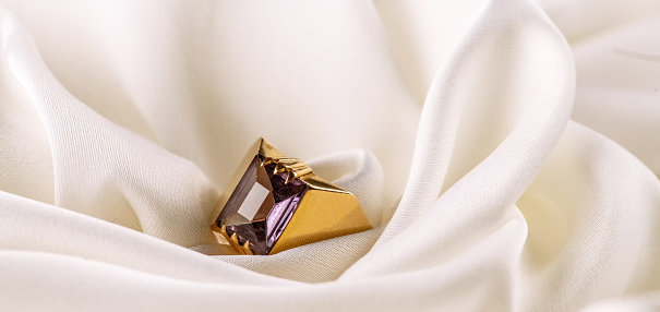 Gold ring with Alexandrite on the background white silk