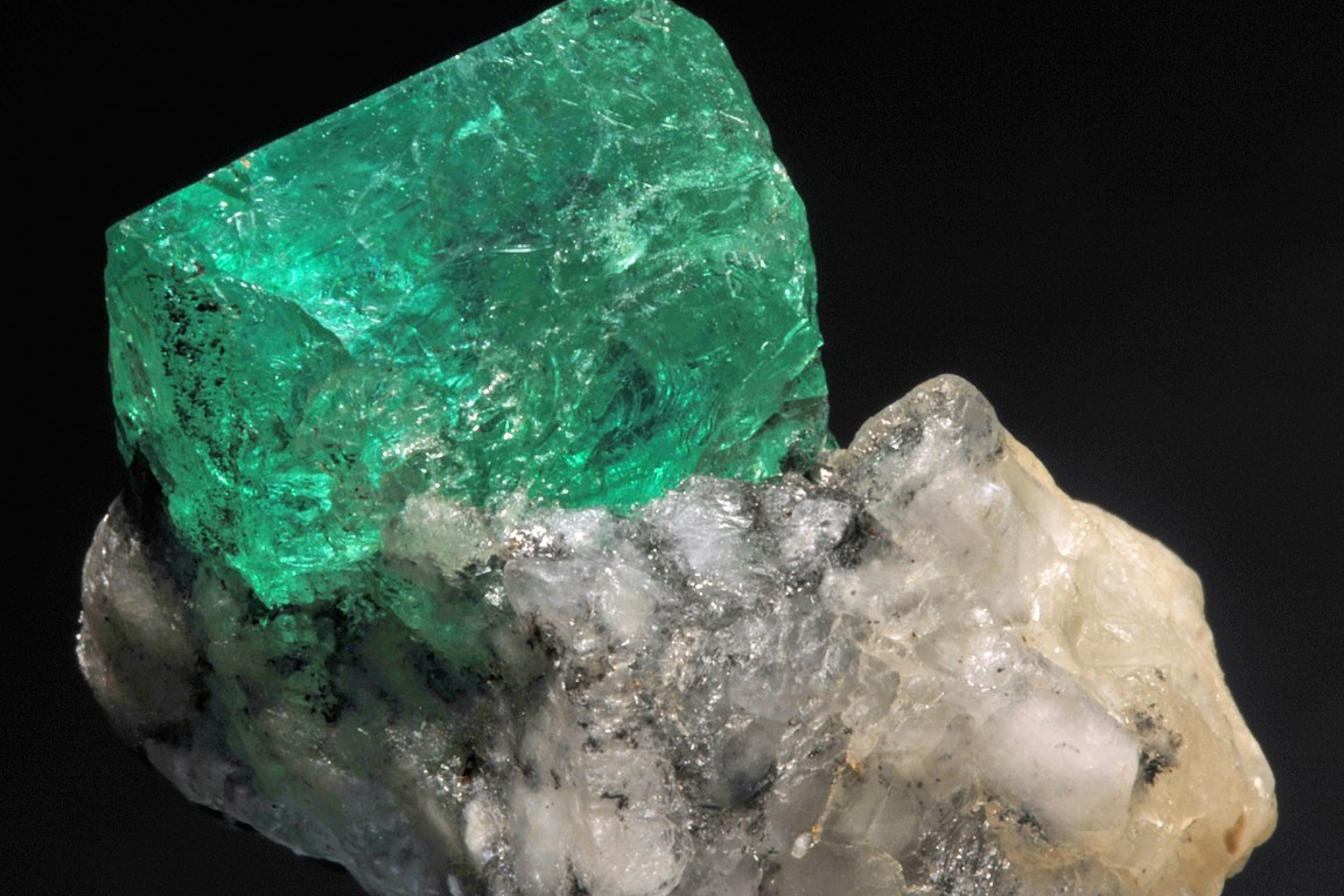 A close-up photograph of an emerald stone attached to its host rock