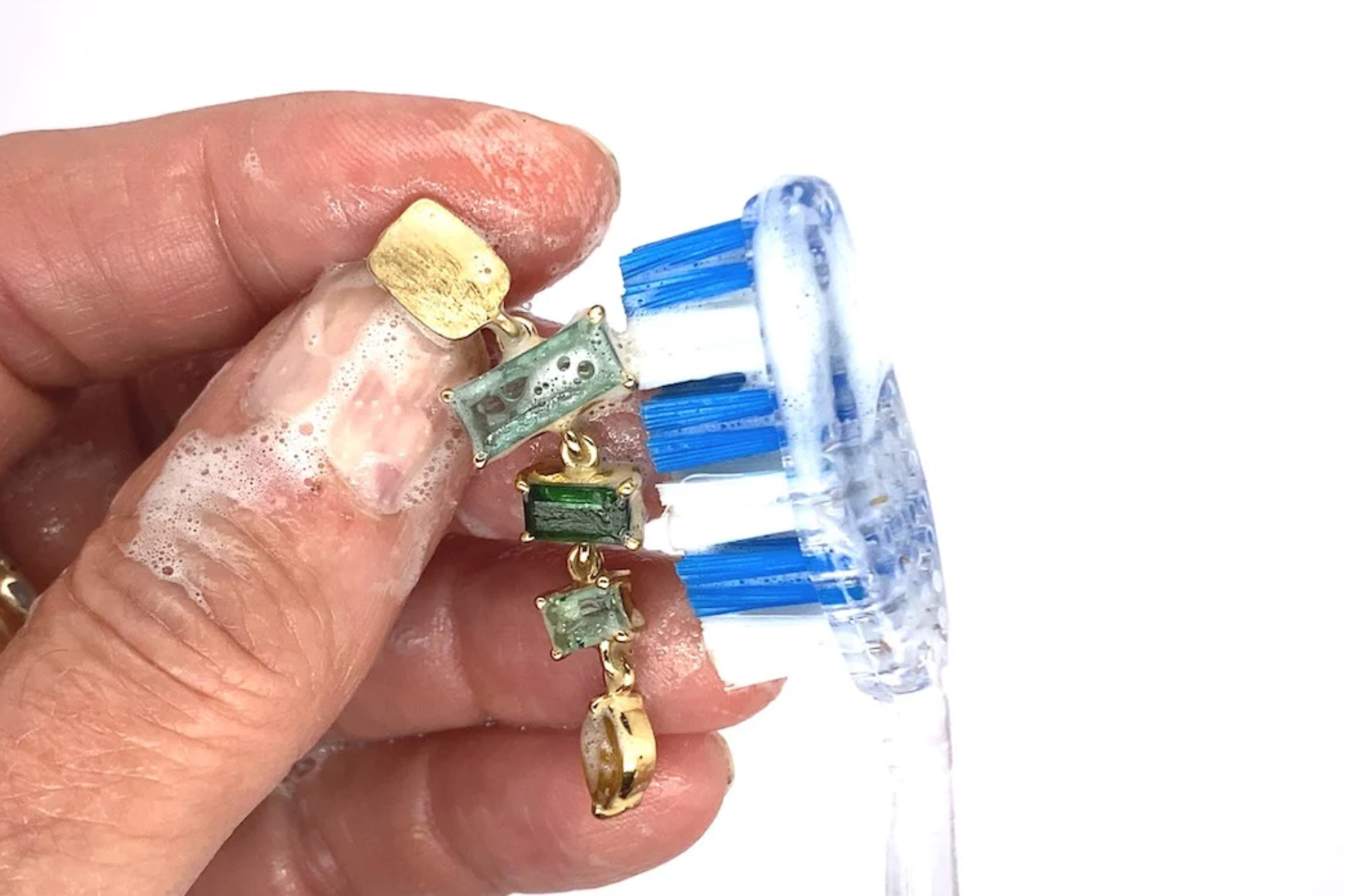 A woman's hand cleaning a birthstone pendant