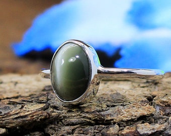 Aesthetic ring with green Catseye sits on top of wood