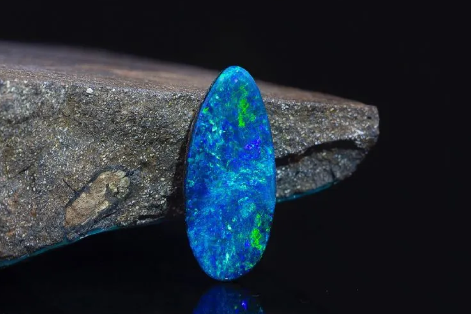 A photograph of an opal stone resting on a rock