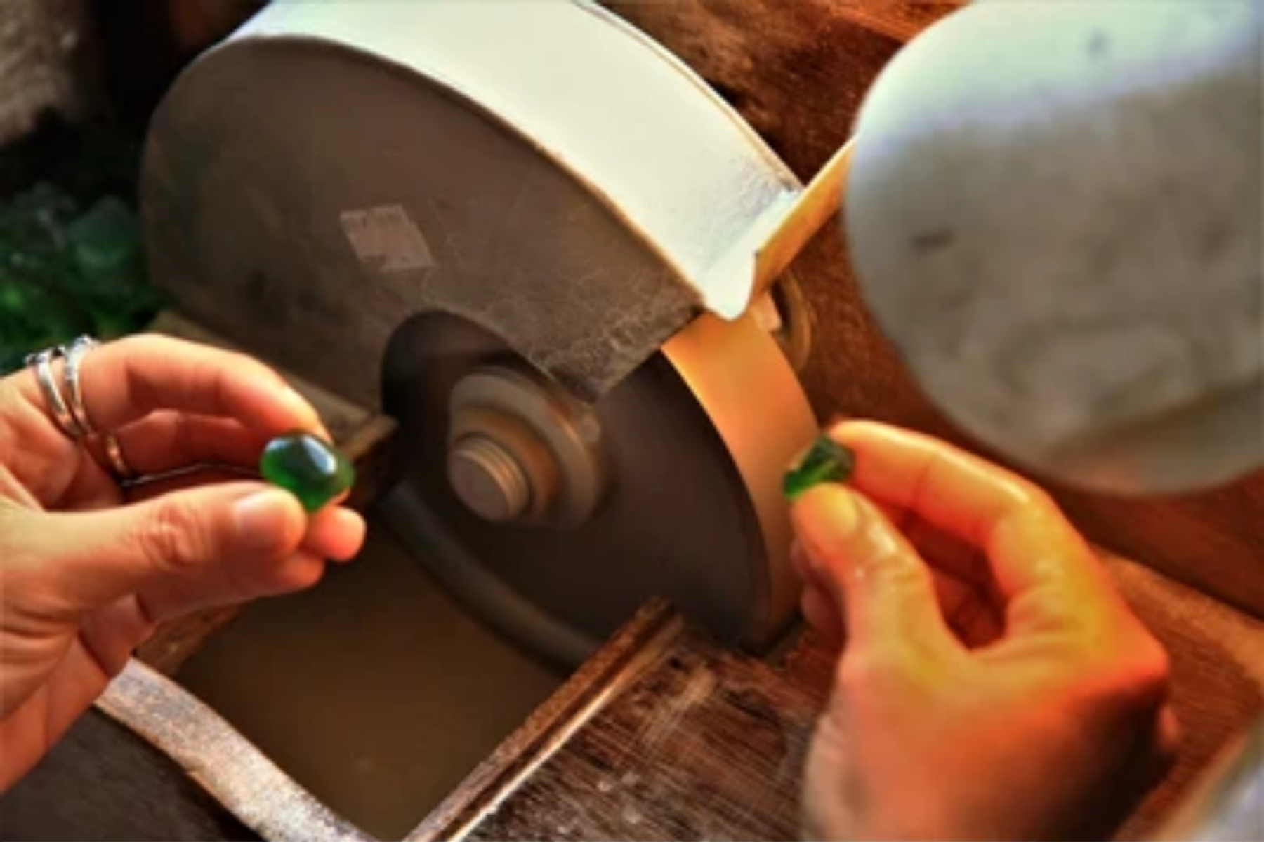A green stone is directly put into a cutting machine while a well-polished green stone is held in the other hand as a reference