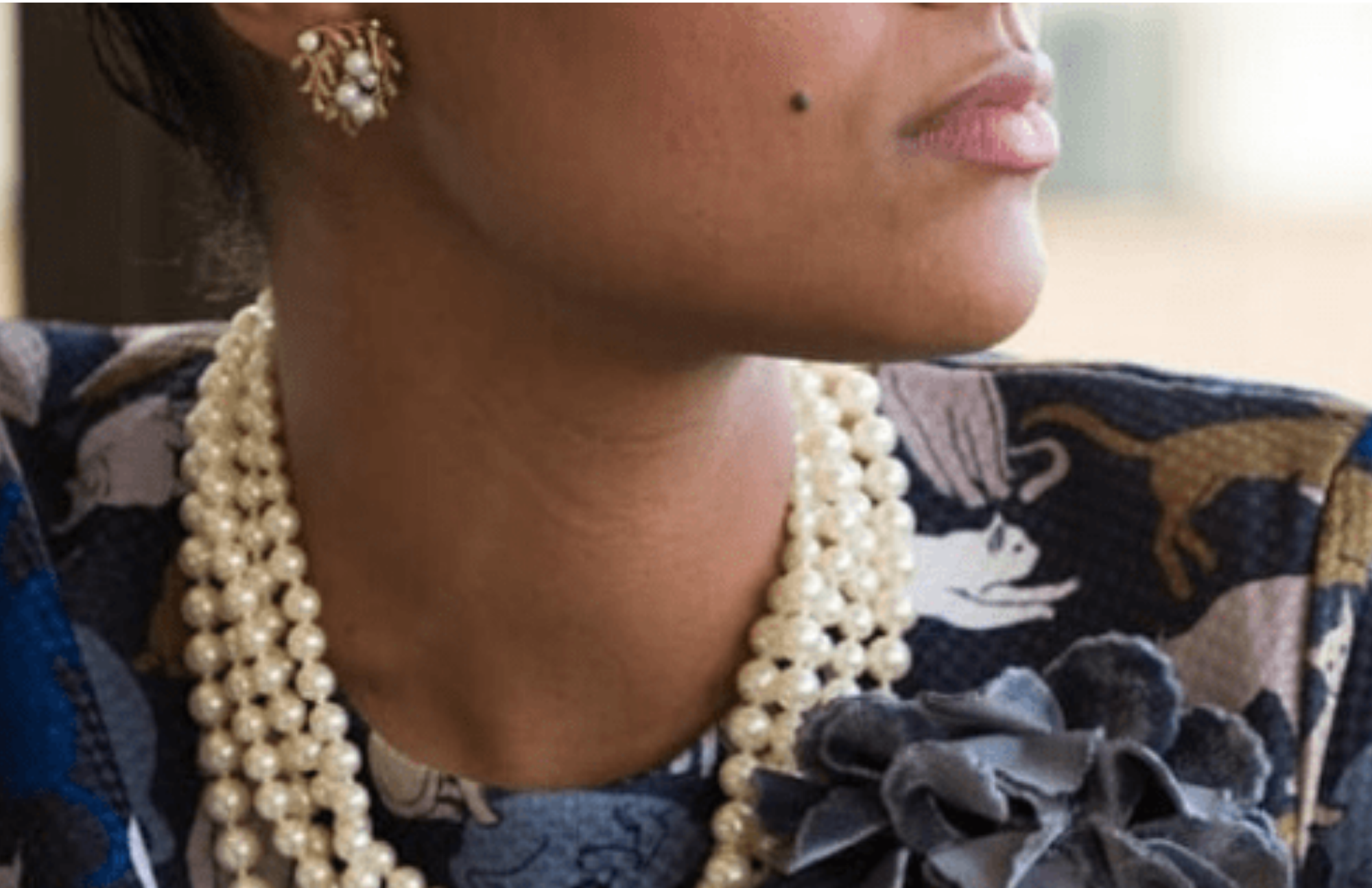 A woman wearing five pearl necklaces and looking to the side