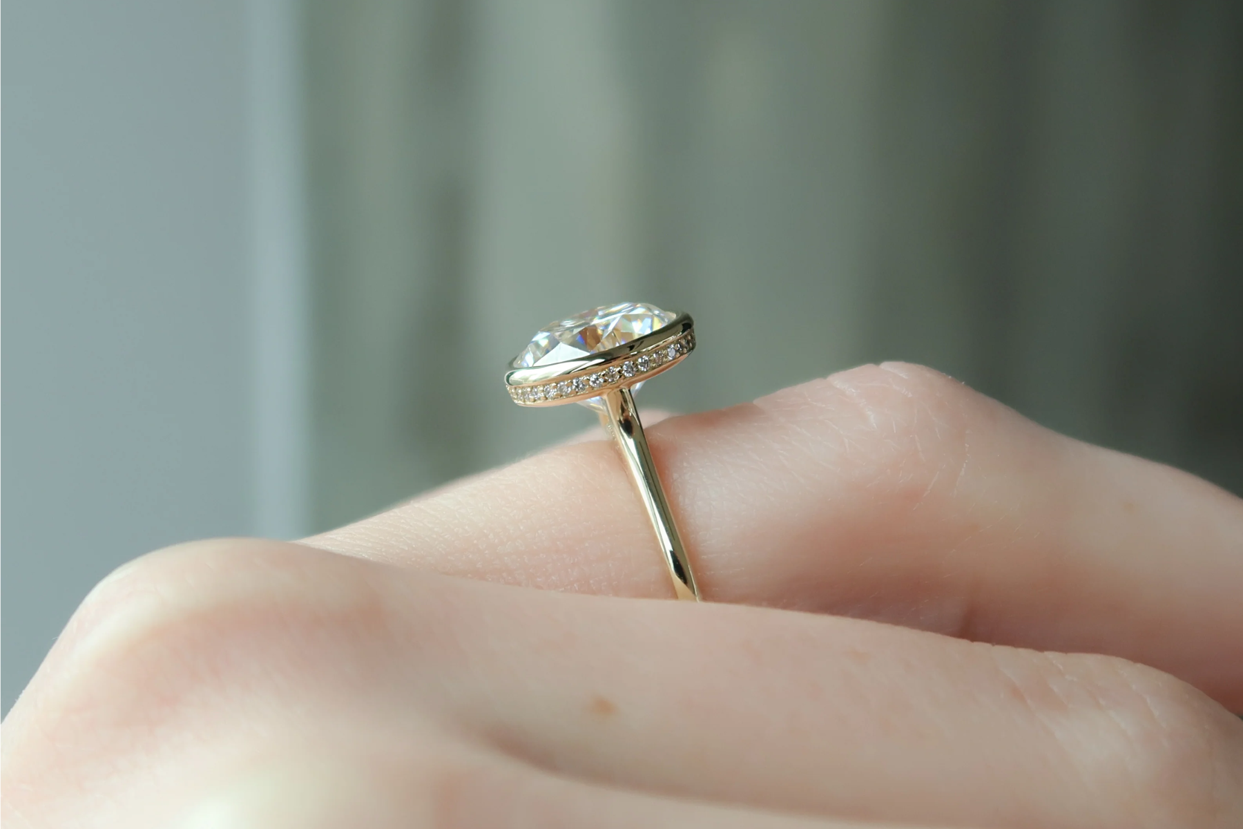 An engagement ring with a bezel setting on a woman's finger