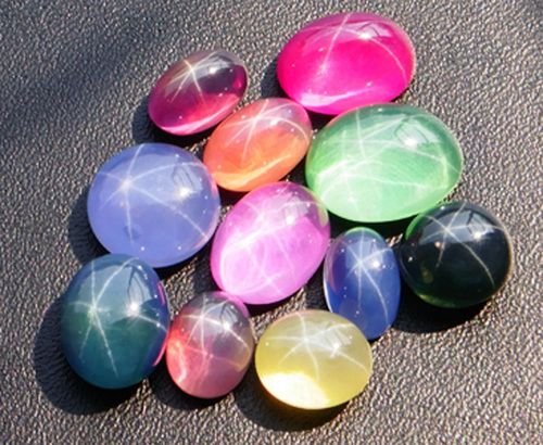 Blue, yellow, green, and pink star sapphires facing the light