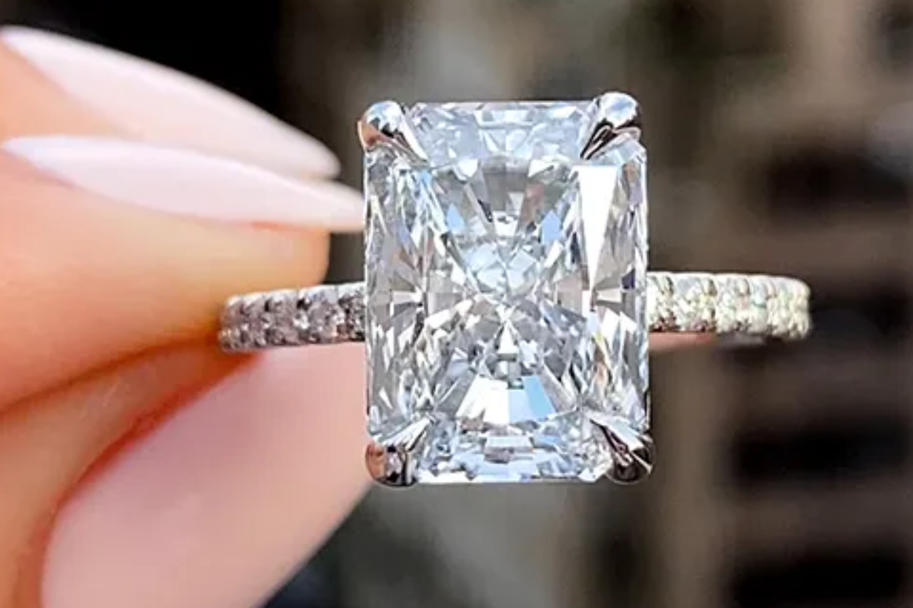 A woman's hand holds a radiant cut diamond ring