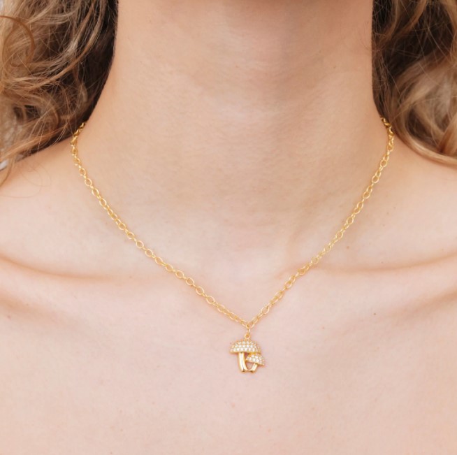 A woman wearing a multiverse mushroom pendant and the gold chain hanging on her neck