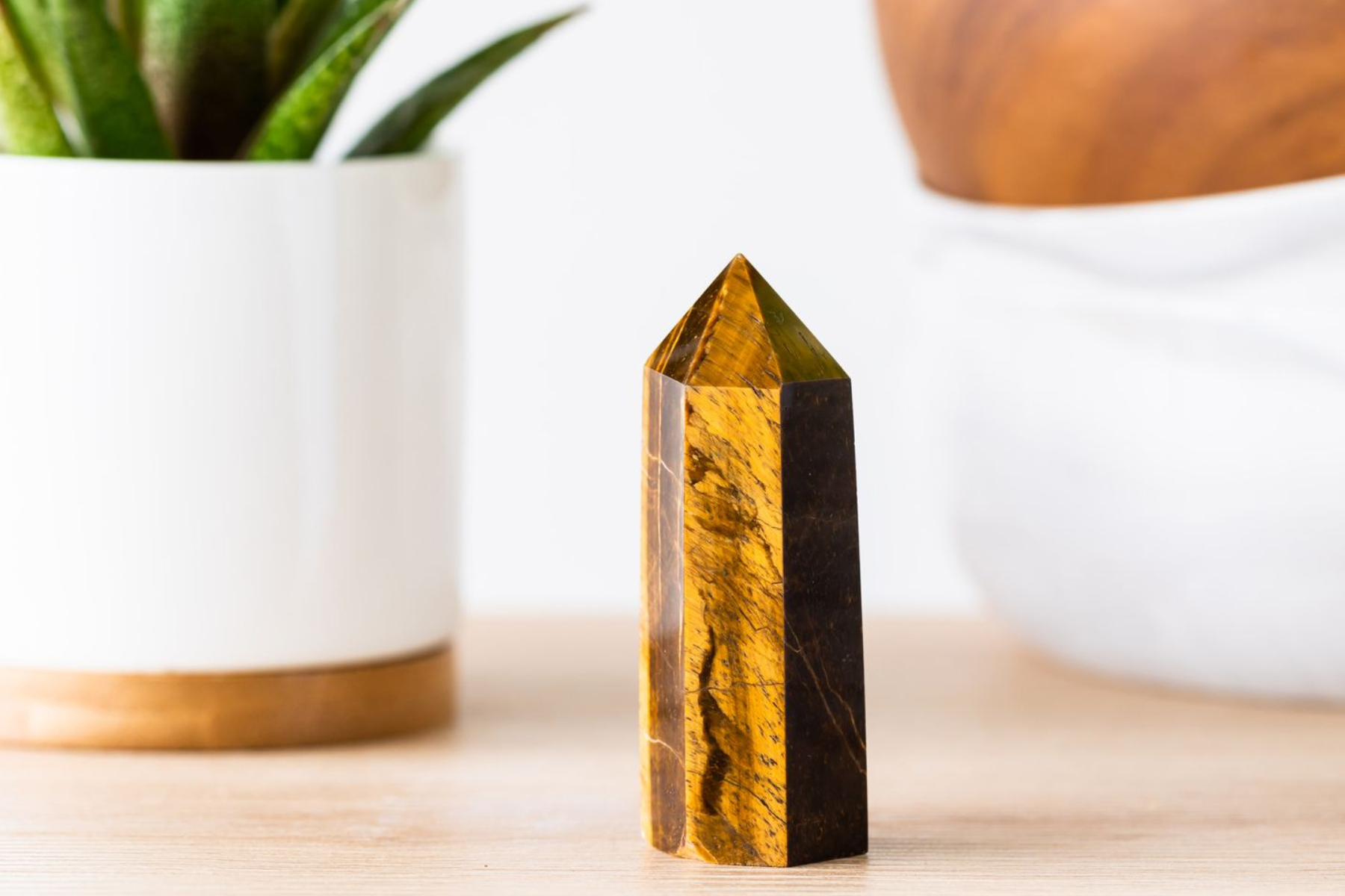 On the table, a Tiger's eye gemstone is surrounded by plants