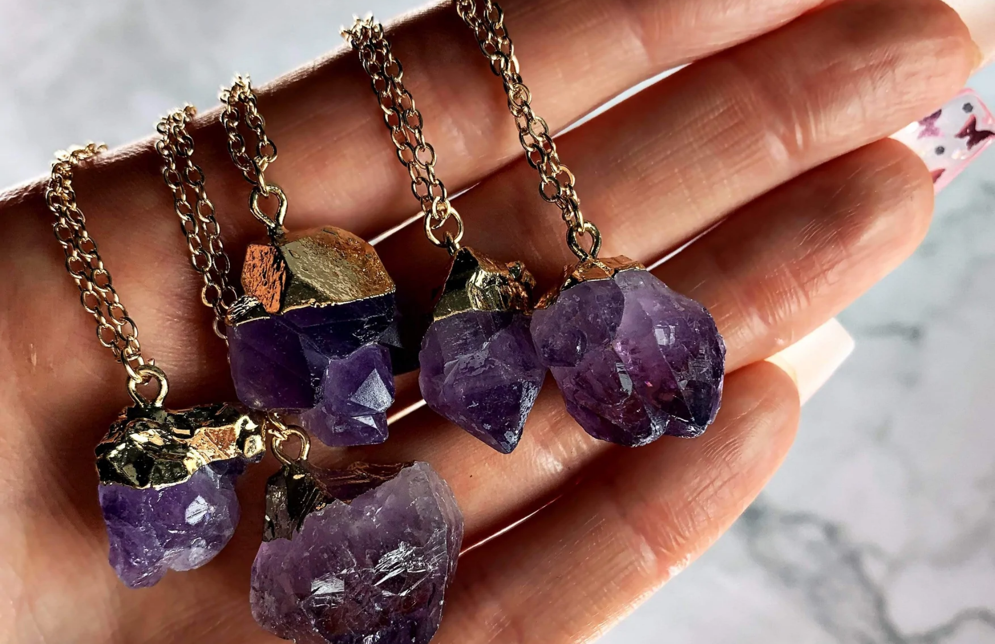 A woman's palm with five amethyst pendants