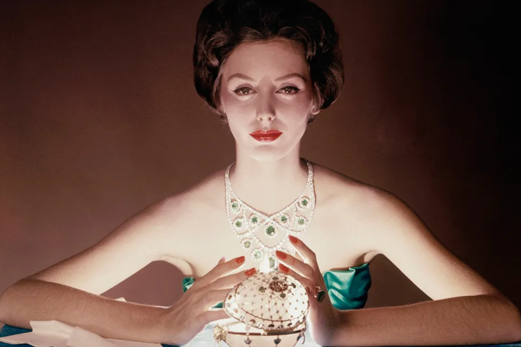 A woman wearing green jewelry and holding a jewelry treasure