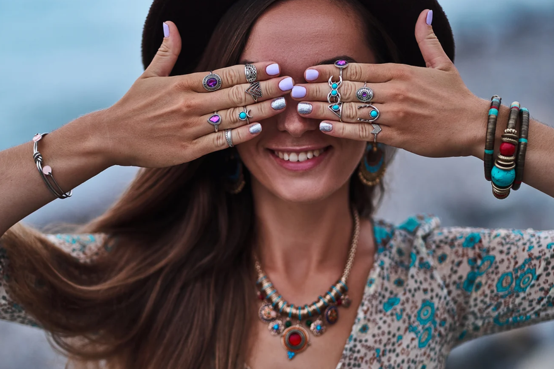 A woman wears many forms of bohemian jewelry while hiding her eyes