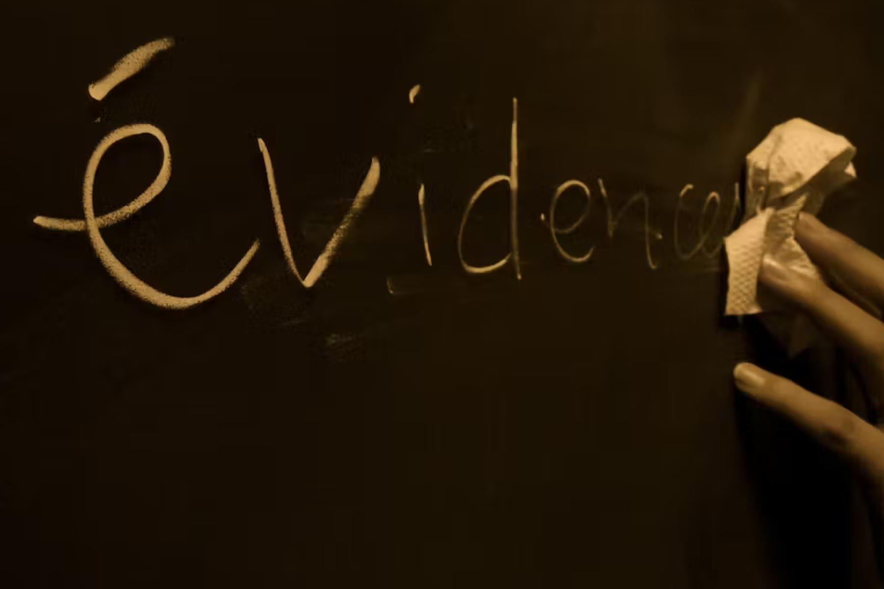 A tissue is being used to clean a black board with the word evidence printed on it