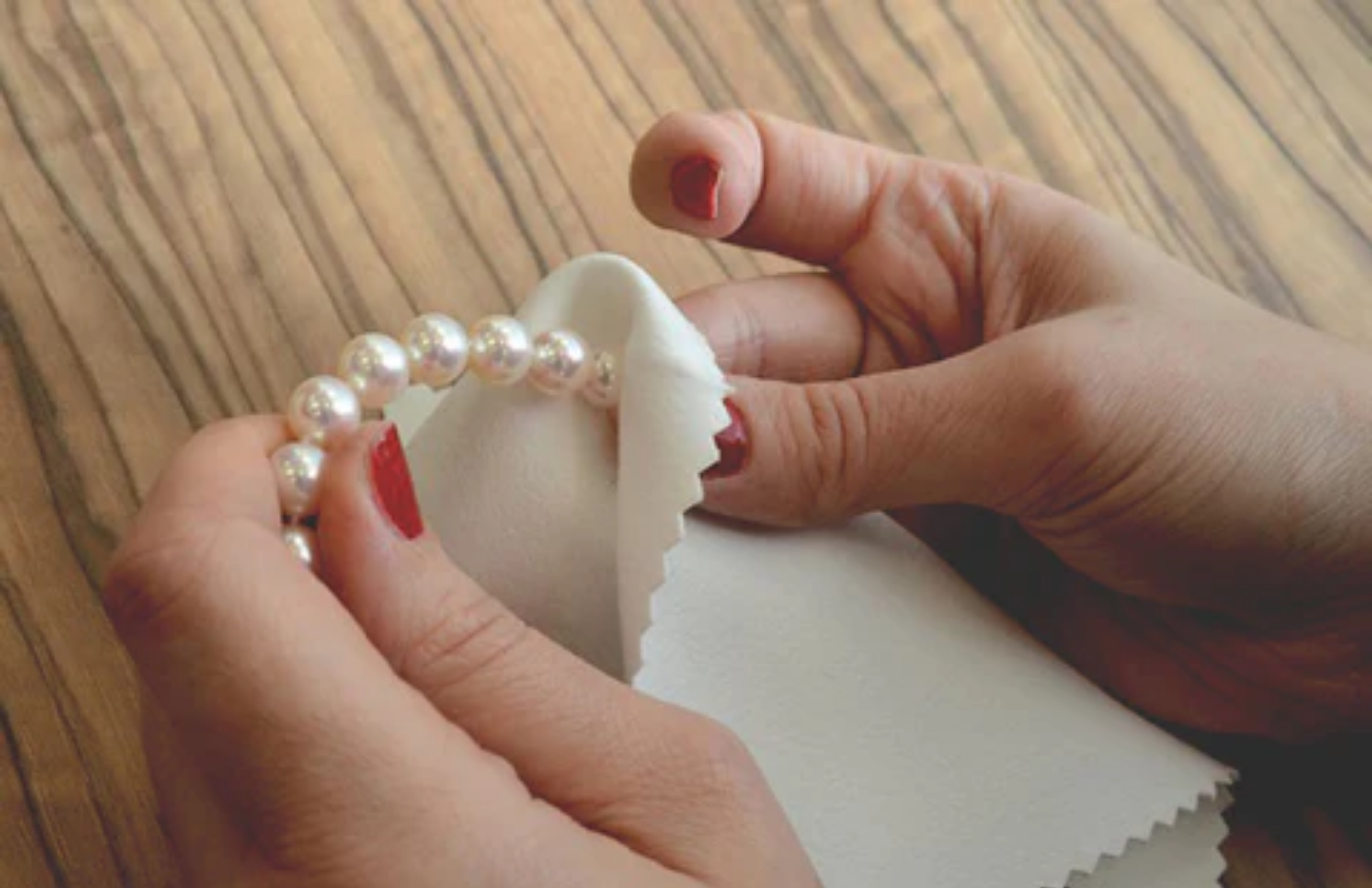 A woman's hand wiping her pearl jewelry