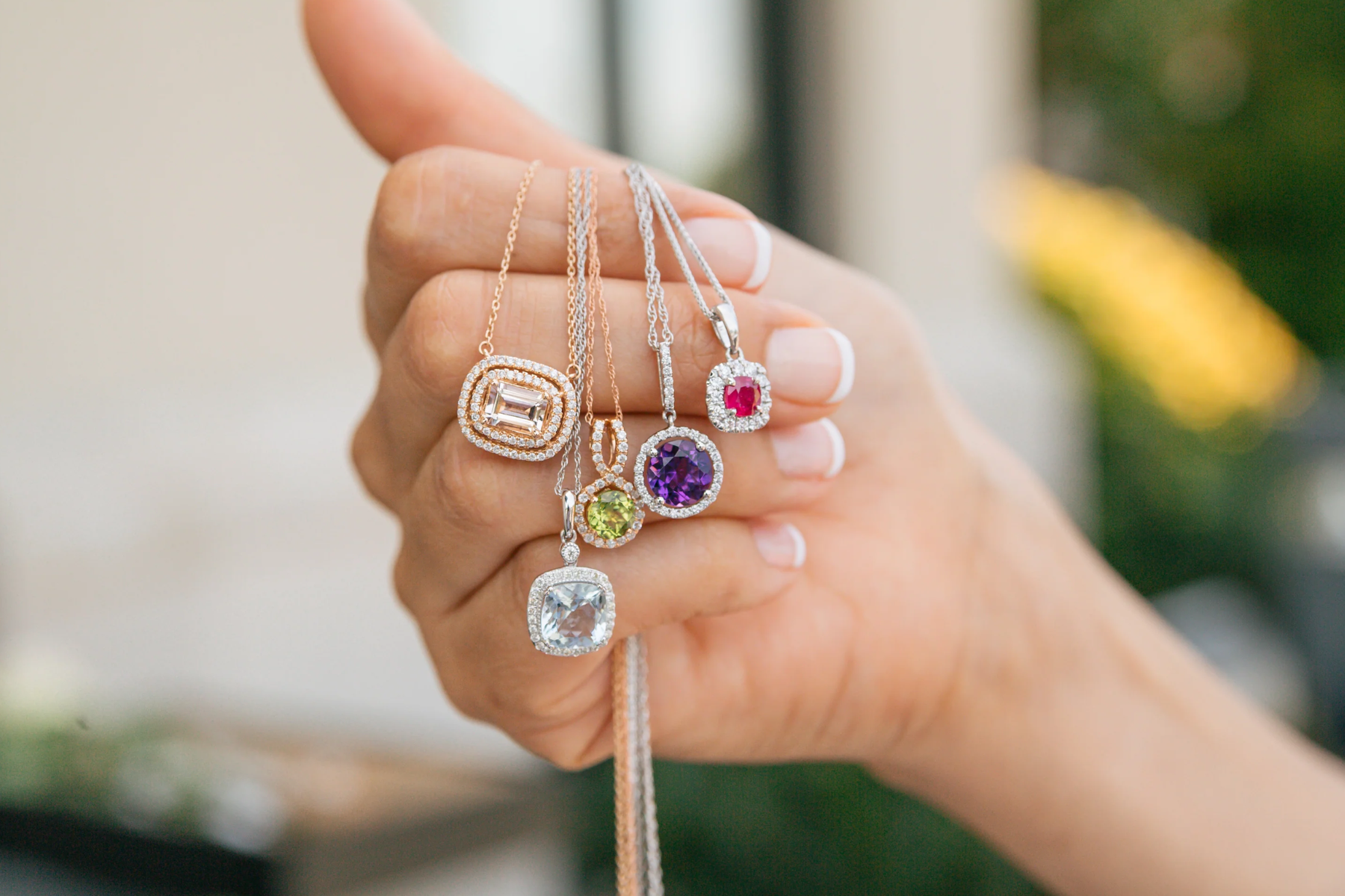 A woman's hand clutching various birthstone necklaces
