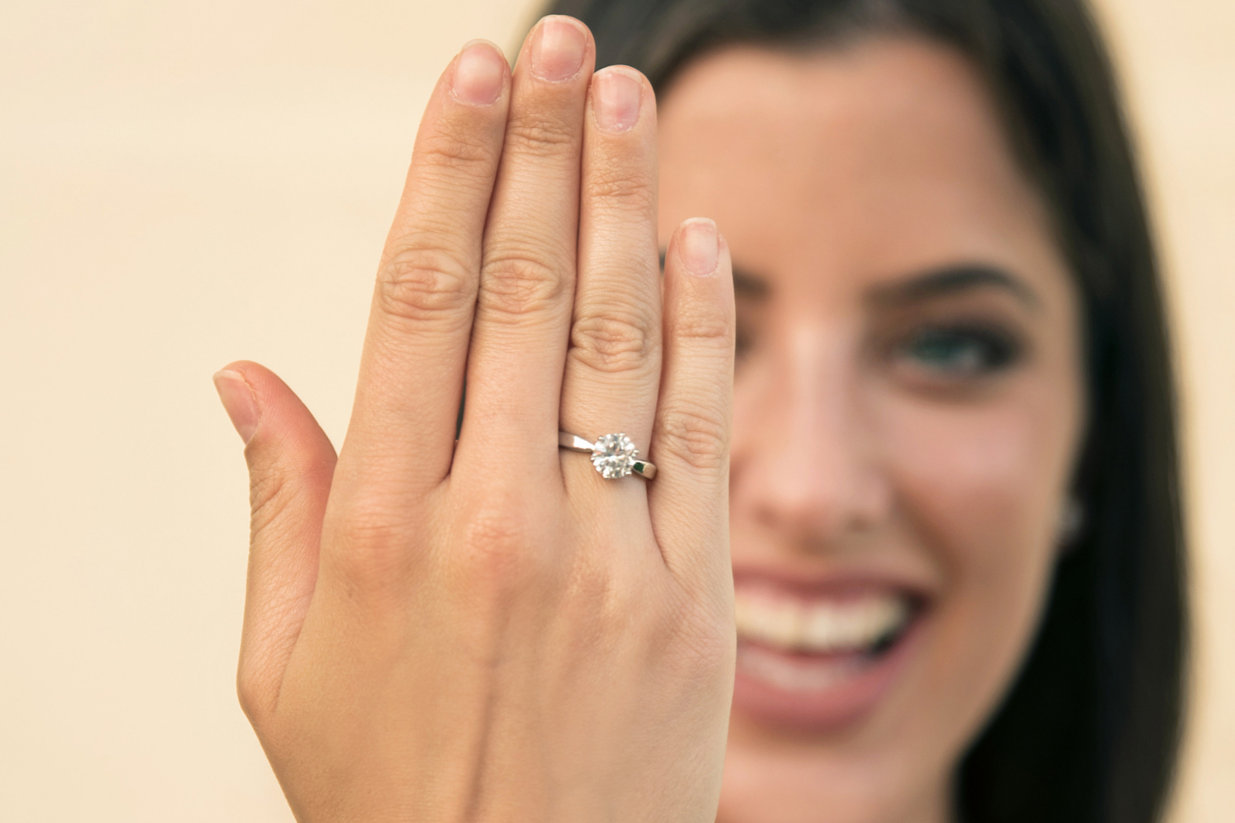 A woman showing a solitaire engagement ring on her finger